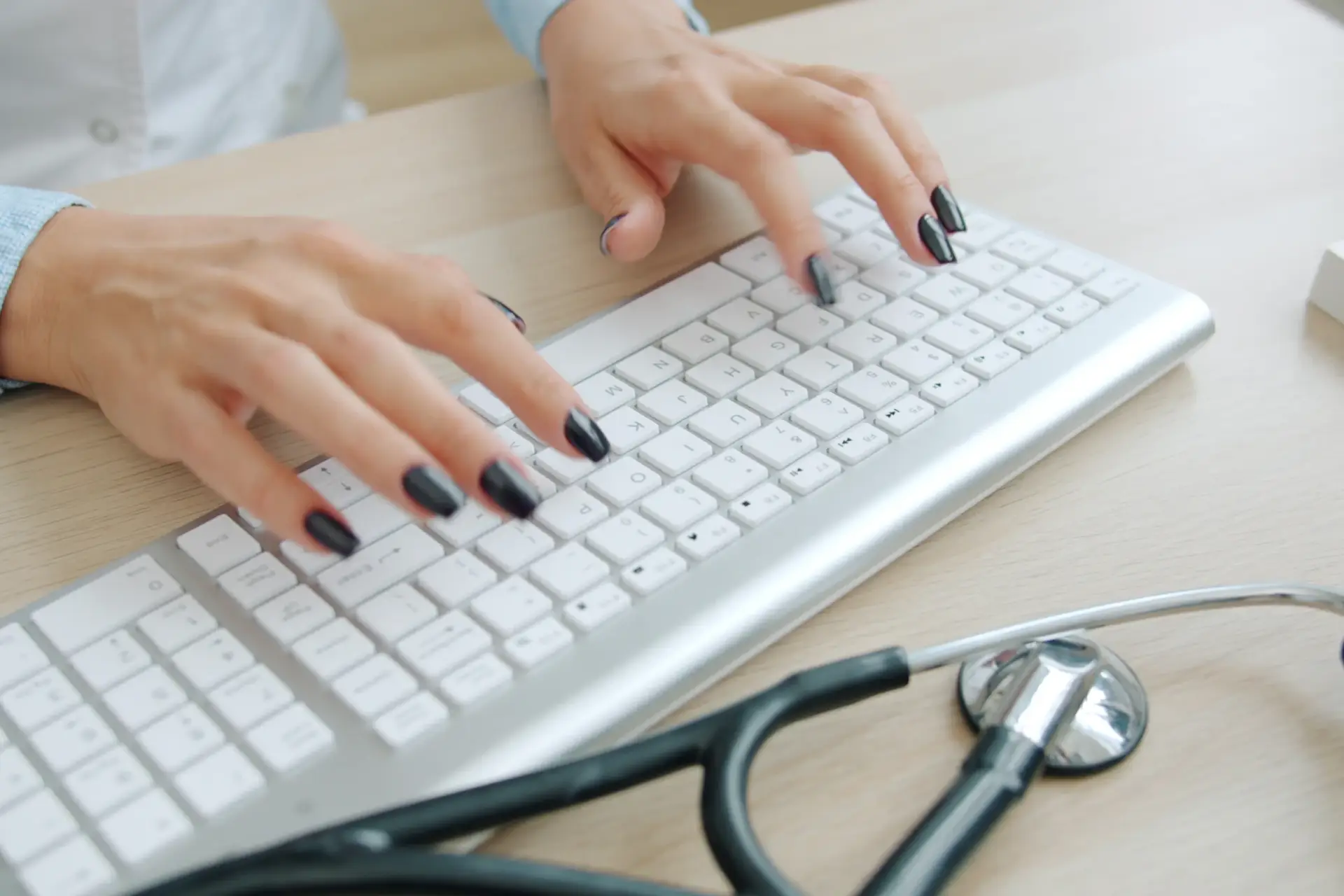Praticien saisissant sur un clavier, stéthoscope posé à côté
